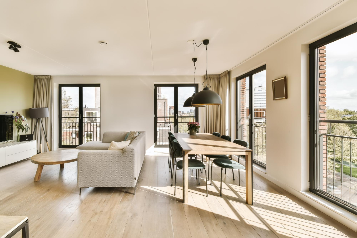 Un salon avec parquet et grandes baies vitrées donnant sur le paysage
